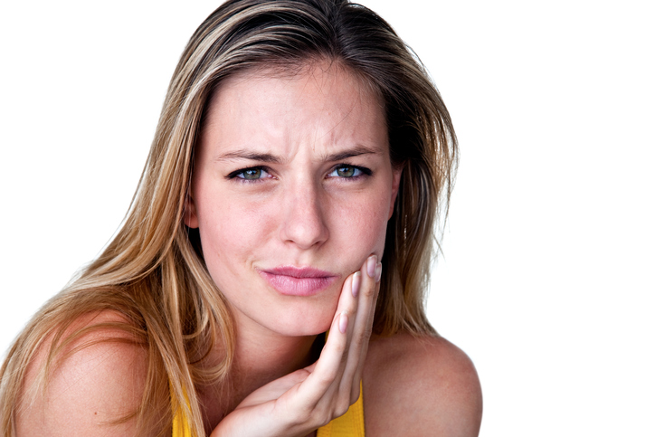 Woman holding cheek with TMJ pain, needing to contact her San Antonio dentist, at Excellent Dental Specialists.